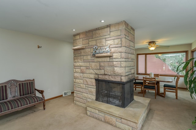 living area with baseboards, visible vents, light colored carpet, ceiling fan, and a stone fireplace