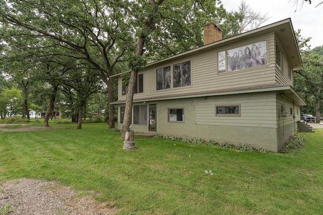 rear view of property with a chimney and a yard