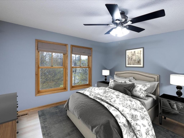 bedroom with hardwood / wood-style flooring, a textured ceiling, and ceiling fan