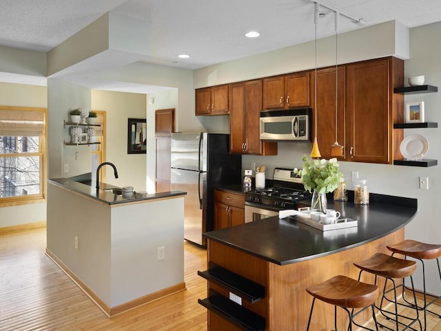 kitchen featuring kitchen peninsula, appliances with stainless steel finishes, a breakfast bar area, and pendant lighting