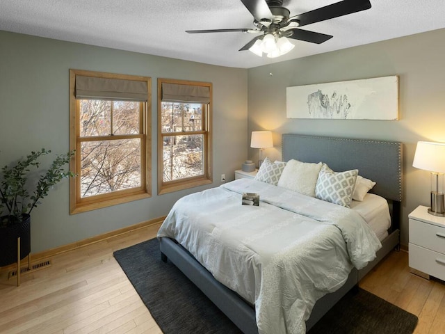 bedroom featuring light hardwood / wood-style flooring, ceiling fan, and a textured ceiling