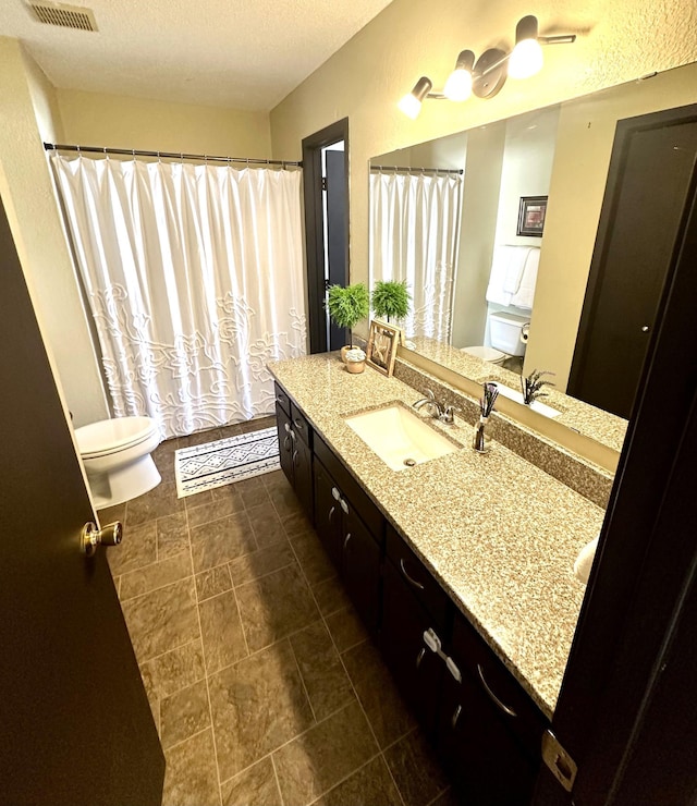 bathroom featuring toilet, a textured ceiling, and vanity