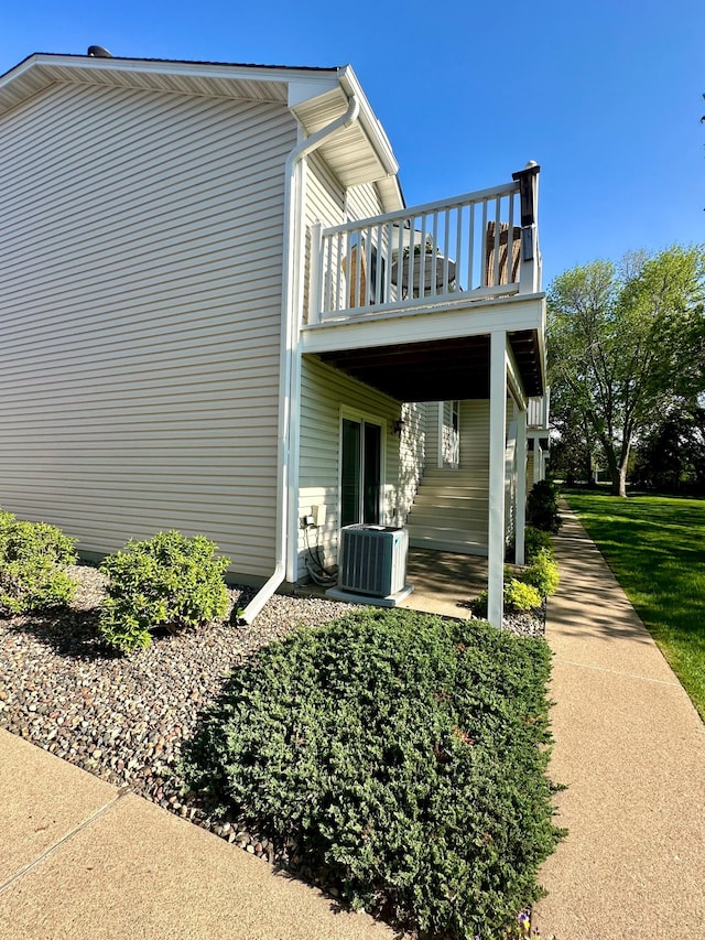 view of property exterior with a balcony, cooling unit, and a patio area