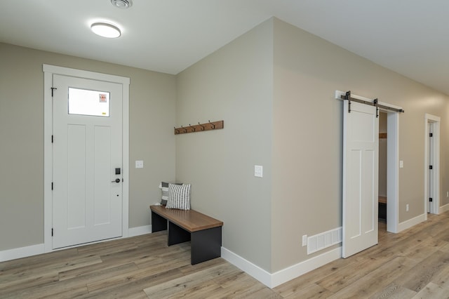 foyer entrance featuring light wood-type flooring and a barn door