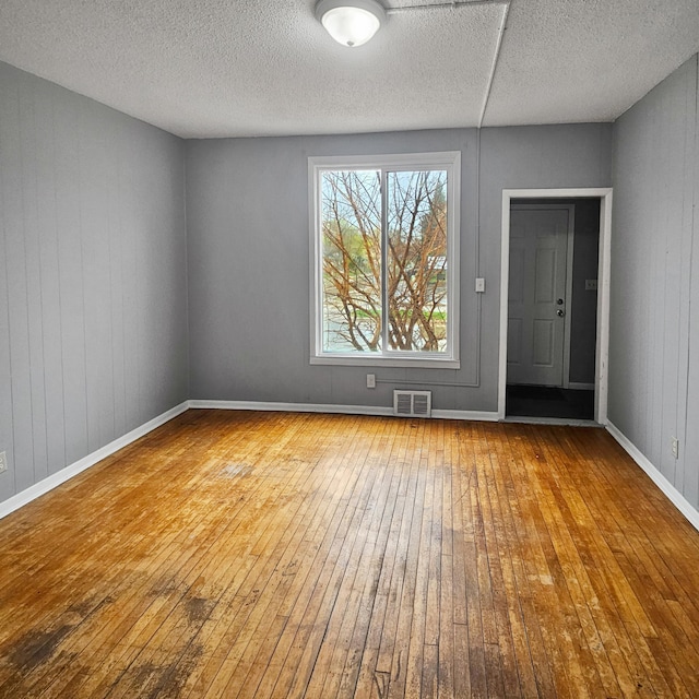 unfurnished room featuring wood-type flooring and a textured ceiling