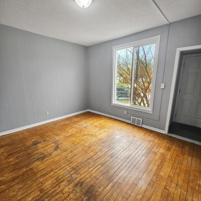 unfurnished room with a textured ceiling and hardwood / wood-style floors