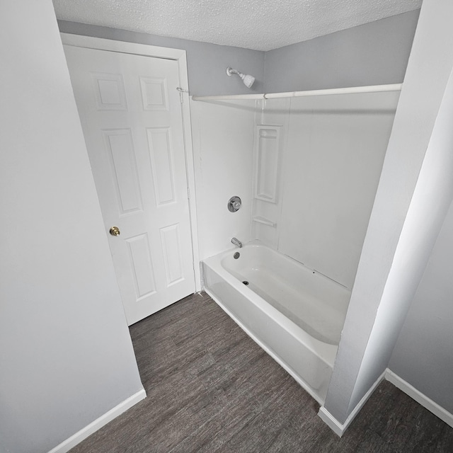 bathroom with shower / tub combination, wood-type flooring, and a textured ceiling