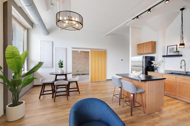 kitchen with sink, a center island, stainless steel fridge, pendant lighting, and light hardwood / wood-style floors