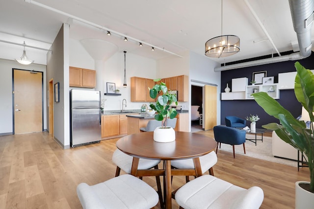 dining space featuring a towering ceiling, light hardwood / wood-style flooring, a notable chandelier, and sink