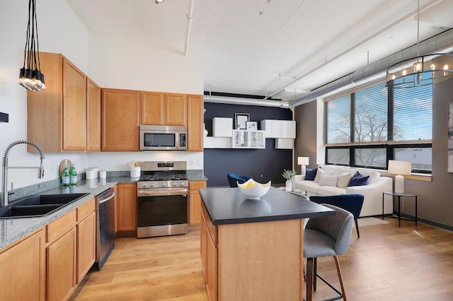 kitchen with sink, decorative light fixtures, a kitchen bar, a kitchen island, and appliances with stainless steel finishes