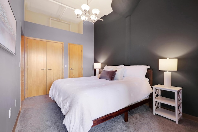 bedroom featuring a chandelier, a towering ceiling, and dark carpet