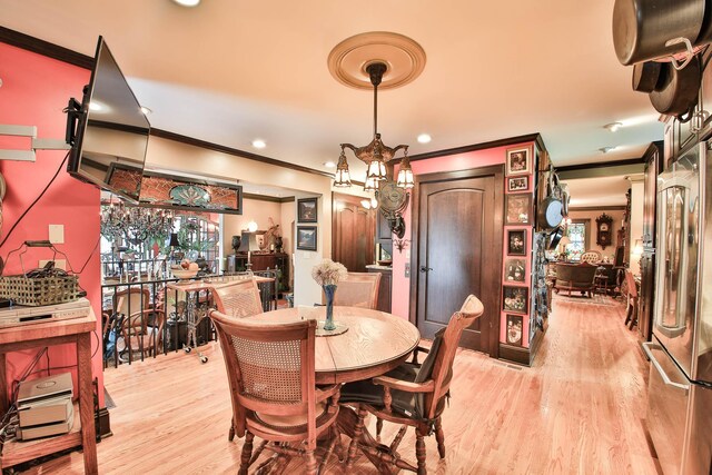 dining room featuring an inviting chandelier, light hardwood / wood-style flooring, and ornamental molding