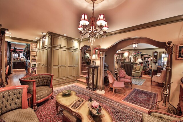 living room with crown molding, wood-type flooring, and a notable chandelier