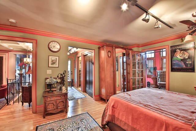 bedroom featuring ornamental molding, light hardwood / wood-style floors, and rail lighting