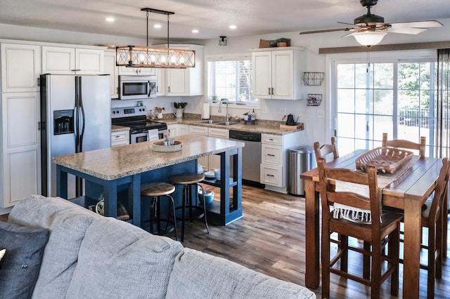 kitchen featuring white cabinetry, sink, dark wood-type flooring, pendant lighting, and appliances with stainless steel finishes