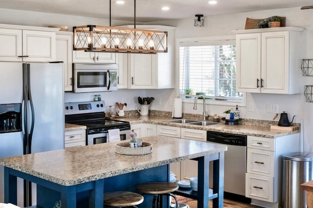 kitchen featuring white cabinetry, a center island, sink, hanging light fixtures, and stainless steel appliances