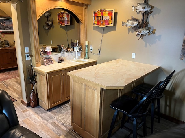 bar with tile countertops, sink, and light hardwood / wood-style floors