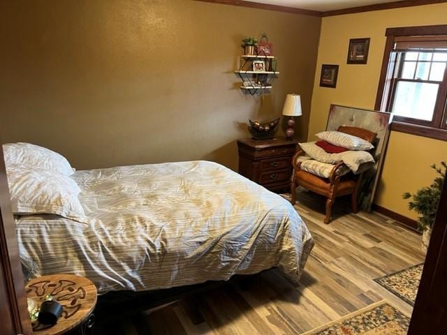 bedroom featuring crown molding and light hardwood / wood-style flooring