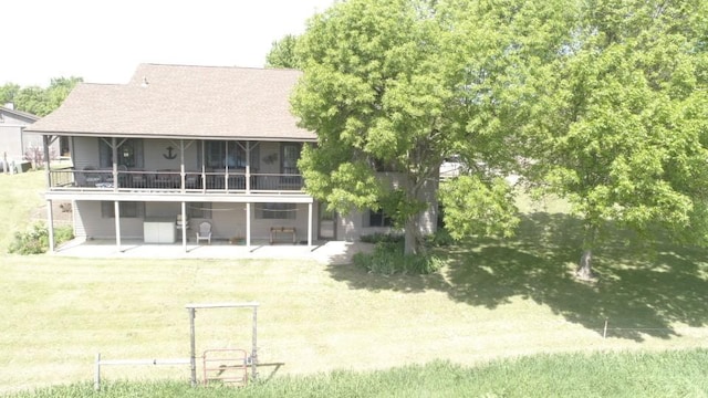 back of property with a lawn, a sunroom, and a patio