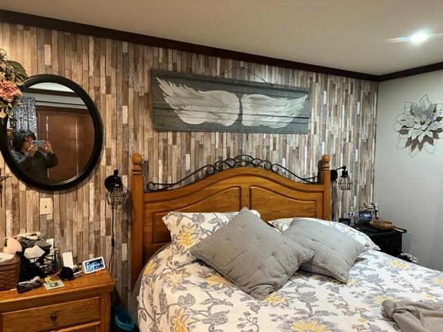 bedroom with crown molding and wood walls