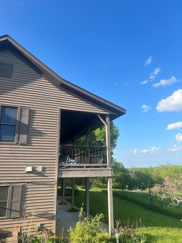 view of side of home with a lawn and a balcony