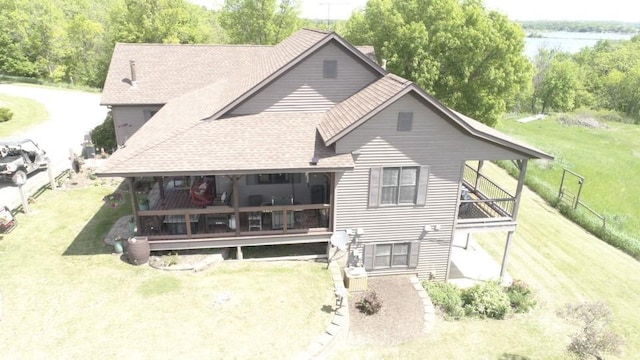 back of house with a water view and a yard