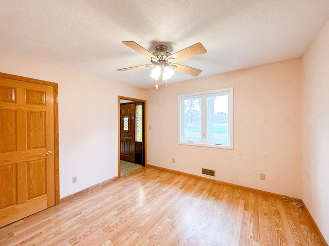 spare room featuring light hardwood / wood-style floors, a textured ceiling, and ceiling fan