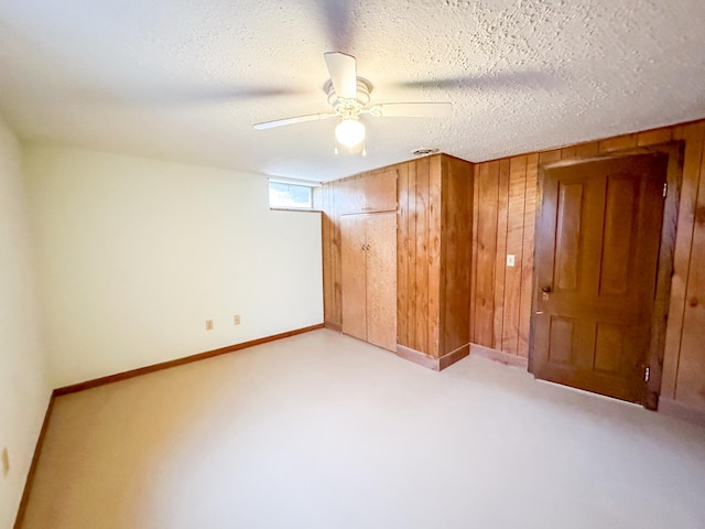 unfurnished bedroom with wood walls, a textured ceiling, and ceiling fan