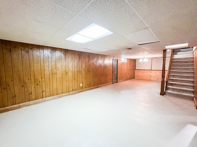 basement with a paneled ceiling and wood walls