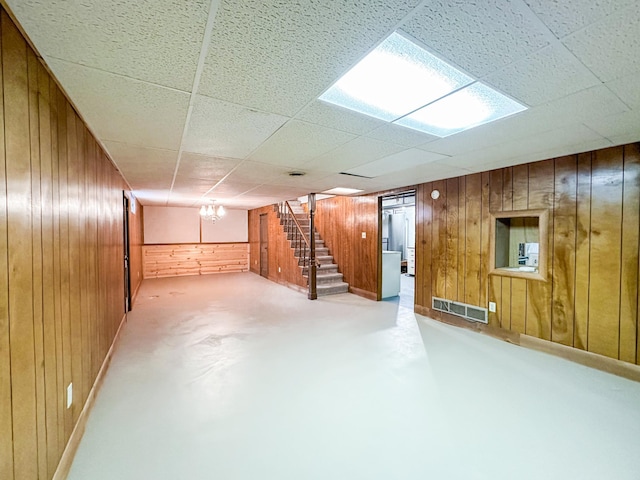 basement with a paneled ceiling and wood walls