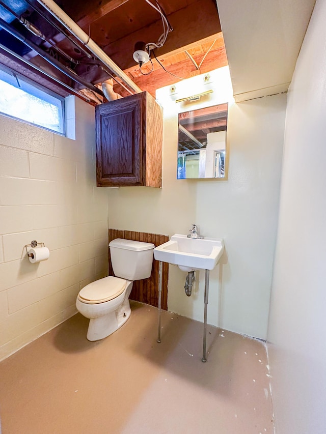 bathroom featuring toilet, sink, and concrete floors