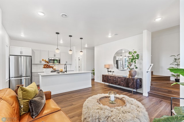 living area with baseboards, wood finished floors, and recessed lighting