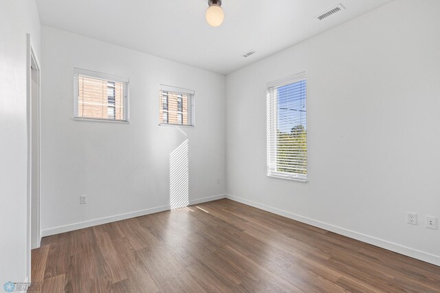 spare room with wood finished floors, baseboards, and visible vents