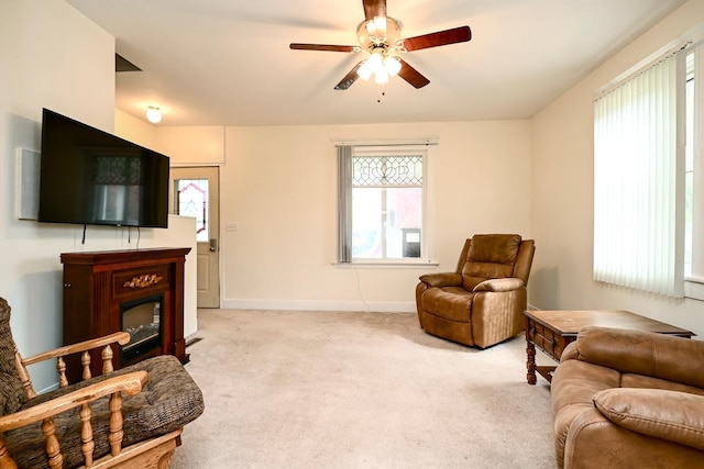 living area featuring light carpet, ceiling fan, and a healthy amount of sunlight