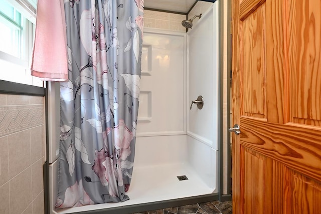 bathroom with tile walls and a shower with shower curtain