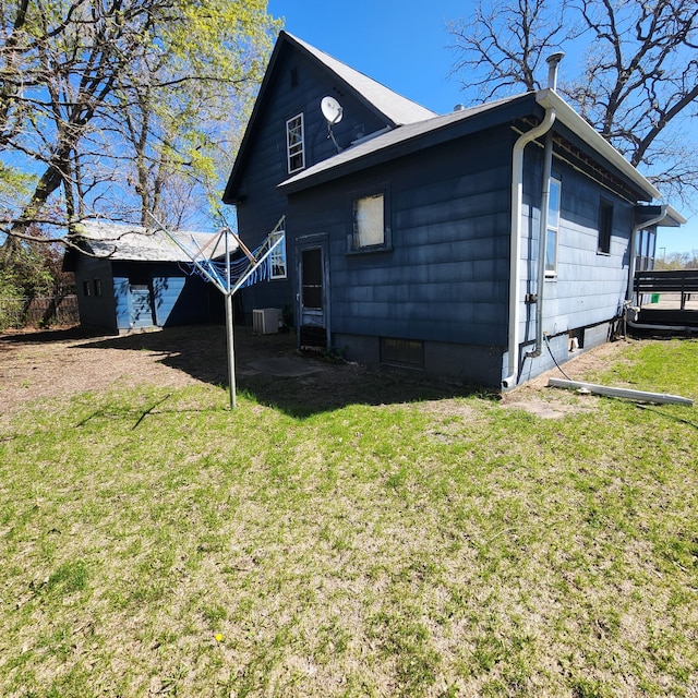 view of side of property with central AC unit and a lawn