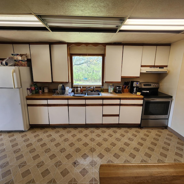 kitchen featuring white fridge, stainless steel electric range oven, white cabinets, sink, and light tile floors