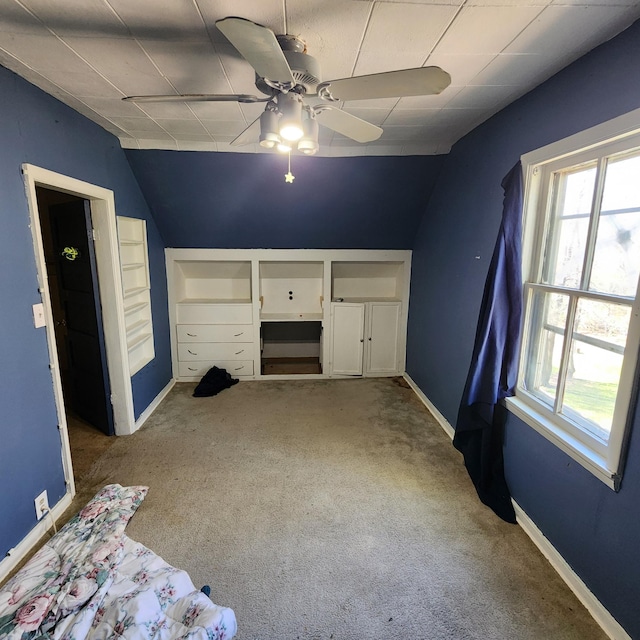 unfurnished bedroom featuring multiple windows, vaulted ceiling, ceiling fan, and carpet flooring