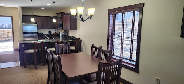 dining room featuring a healthy amount of sunlight, an inviting chandelier, and carpet flooring