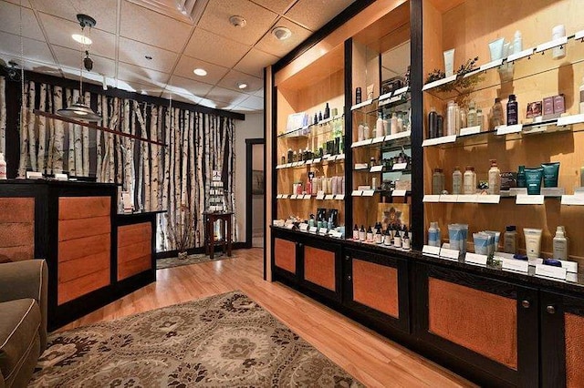 wine room with hardwood / wood-style flooring and a paneled ceiling