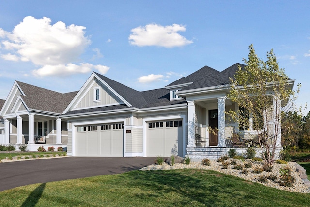 view of front of property with a porch, a front yard, and a garage