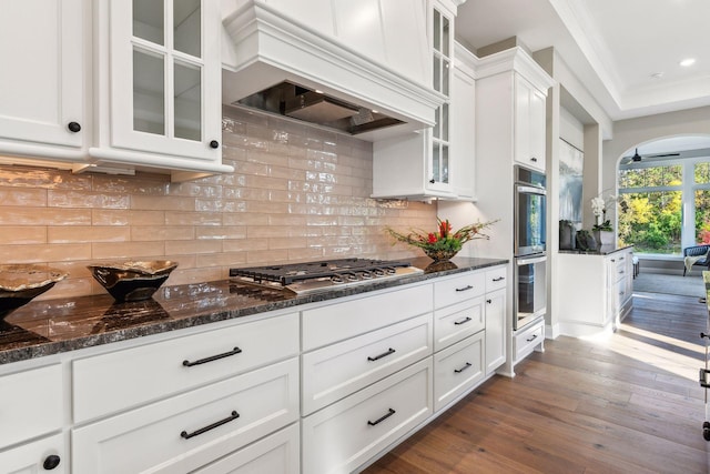 kitchen with tasteful backsplash, white cabinetry, stainless steel appliances, dark hardwood / wood-style floors, and dark stone counters