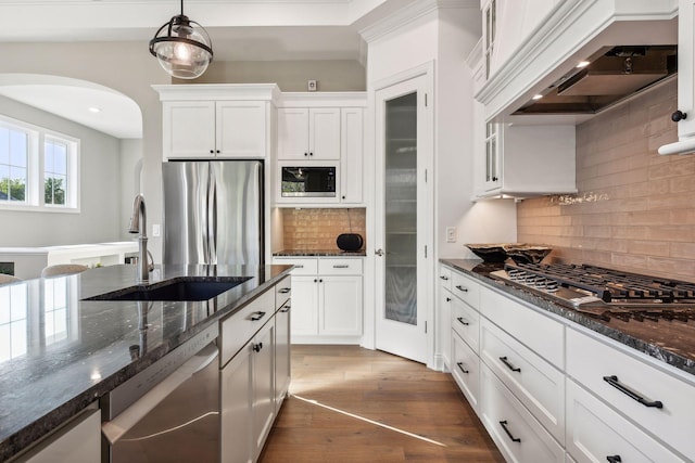 kitchen with decorative light fixtures, dark wood-type flooring, white cabinetry, appliances with stainless steel finishes, and dark stone countertops