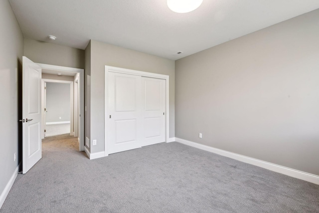 unfurnished bedroom with light carpet and a closet