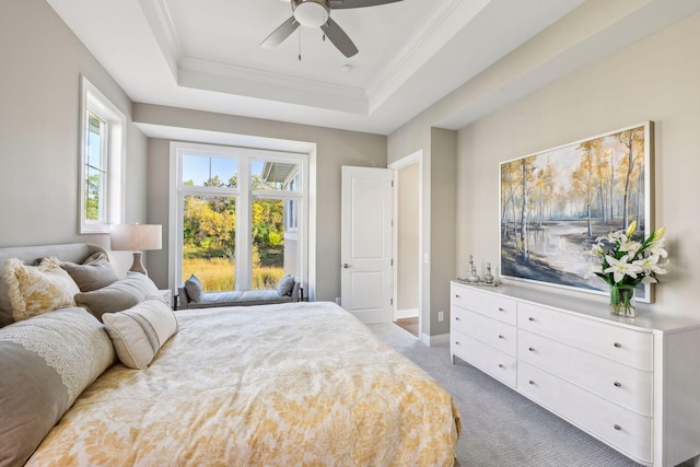 carpeted bedroom with ornamental molding, a tray ceiling, and ceiling fan