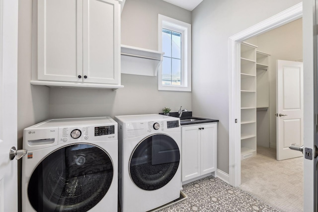 clothes washing area featuring washing machine and dryer, sink, and cabinets