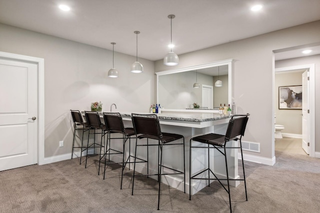 bar featuring light colored carpet and decorative light fixtures