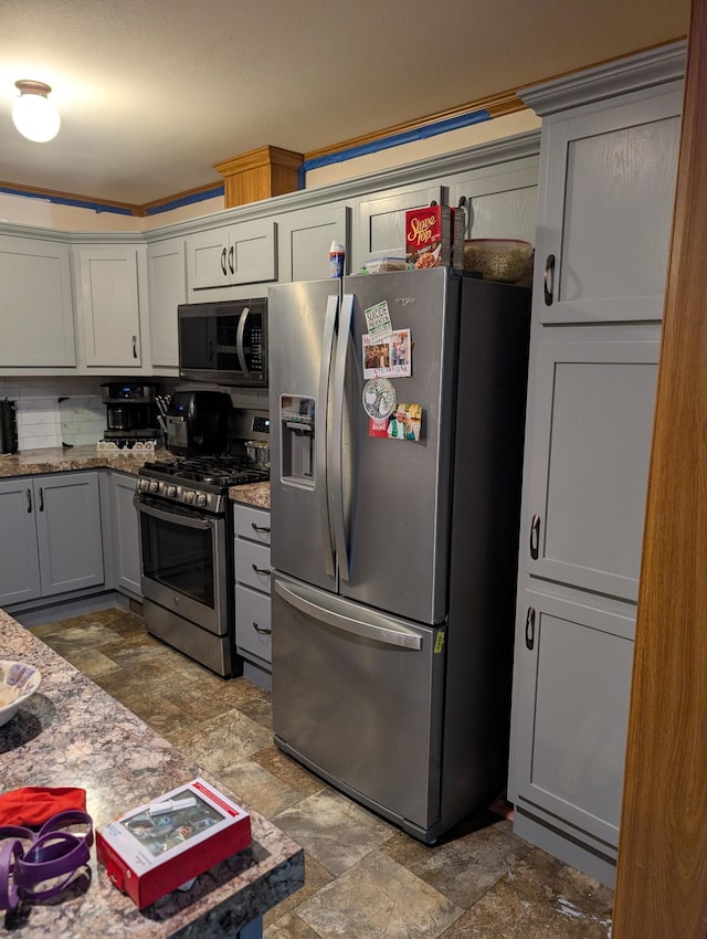 kitchen with light stone counters, stainless steel appliances, and gray cabinets