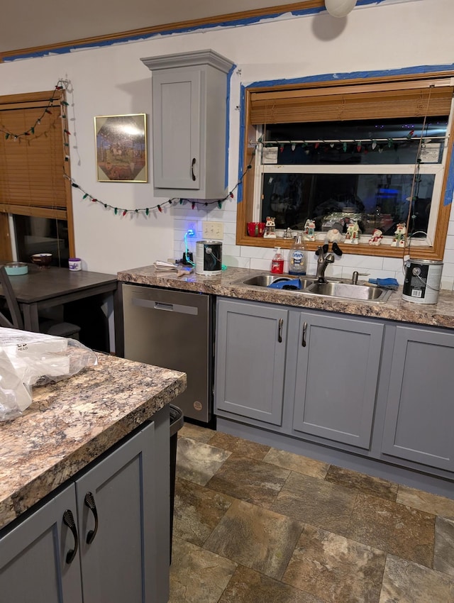 kitchen featuring gray cabinets, dishwasher, sink, and backsplash