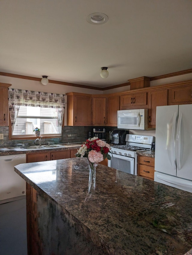 kitchen with sink, crown molding, white appliances, backsplash, and dark stone counters